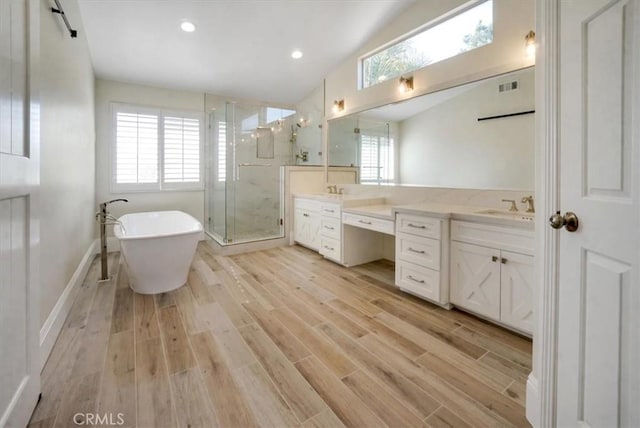 bathroom featuring hardwood / wood-style floors, vaulted ceiling, vanity, and plus walk in shower