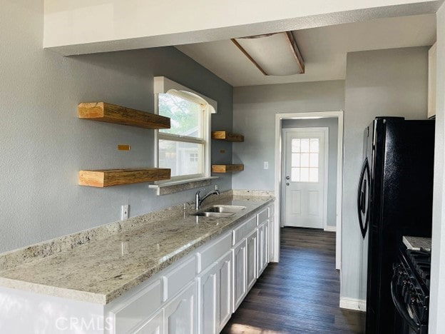 kitchen featuring dark wood-type flooring, light stone countertops, range, white cabinets, and sink