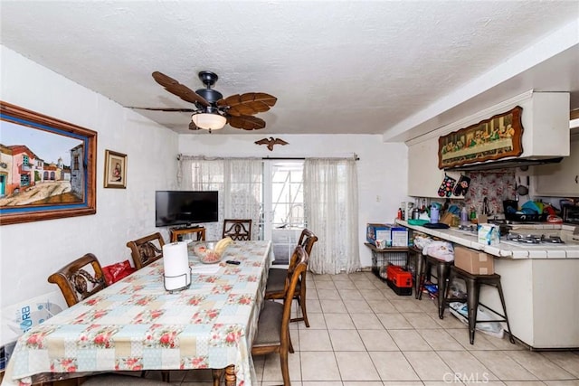 dining area featuring a textured ceiling, ceiling fan, and light tile patterned flooring