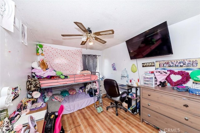 bedroom with light wood-type flooring, ceiling fan, and a textured ceiling