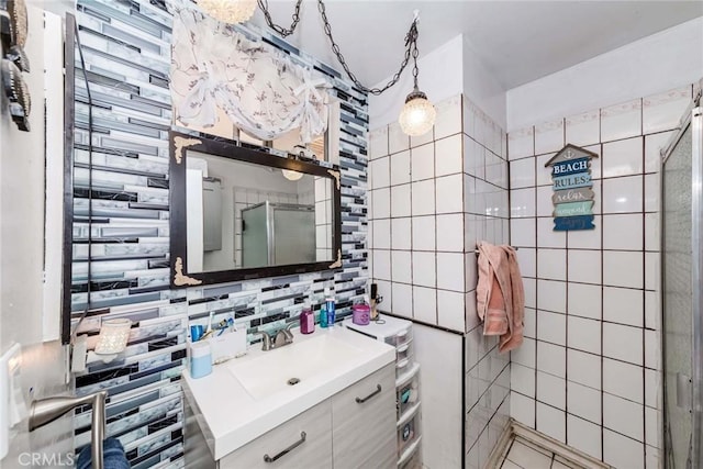 bathroom featuring decorative backsplash, tile walls, walk in shower, and vanity