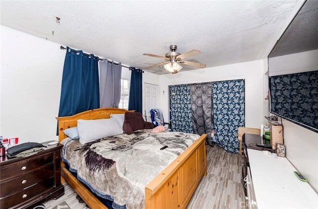 bedroom with a textured ceiling, ceiling fan, and light wood-type flooring