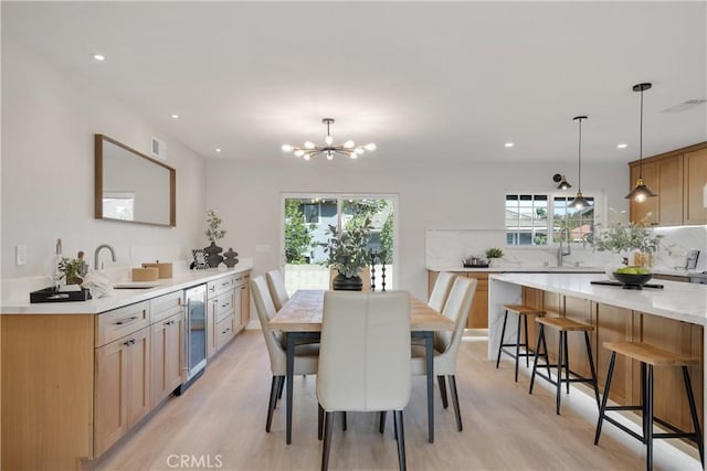 dining area with light hardwood / wood-style floors, a wealth of natural light, a chandelier, and wine cooler