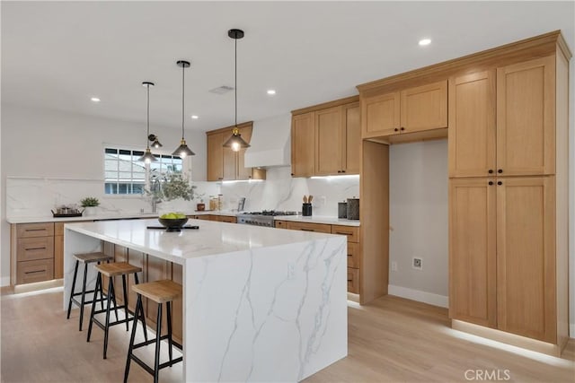 kitchen featuring custom exhaust hood, a kitchen island, tasteful backsplash, light hardwood / wood-style flooring, and stove