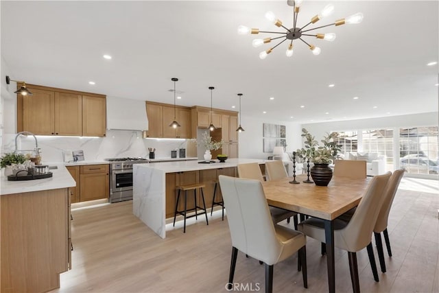 dining room featuring a notable chandelier, sink, and light hardwood / wood-style floors