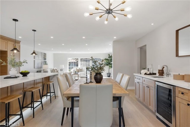 dining area with light hardwood / wood-style floors, sink, a chandelier, and wine cooler