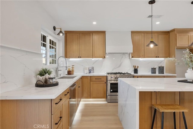 kitchen with stainless steel appliances, decorative backsplash, hanging light fixtures, wall chimney range hood, and sink