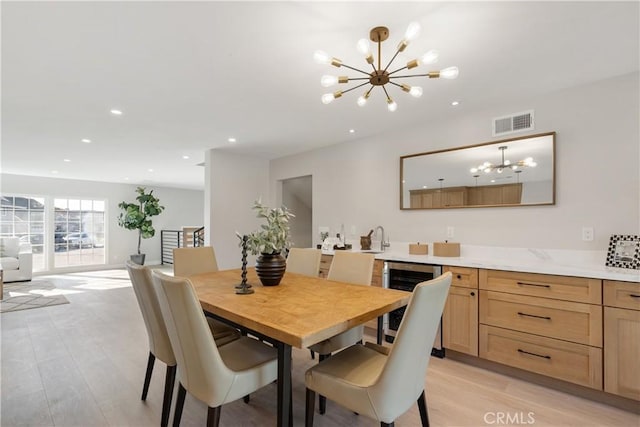 dining space with wine cooler, a notable chandelier, and sink