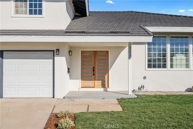 entrance to property featuring a garage, french doors, and a yard