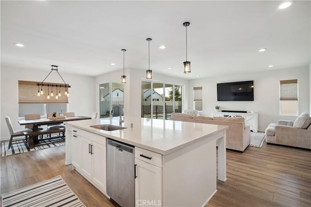 kitchen featuring pendant lighting, white cabinets, an island with sink, sink, and stainless steel dishwasher