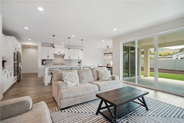 living room with light wood-type flooring and a chandelier