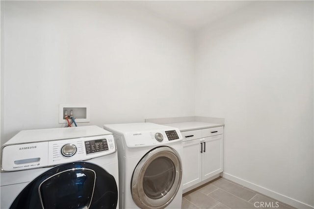 clothes washing area with washing machine and dryer, cabinets, and light tile patterned floors