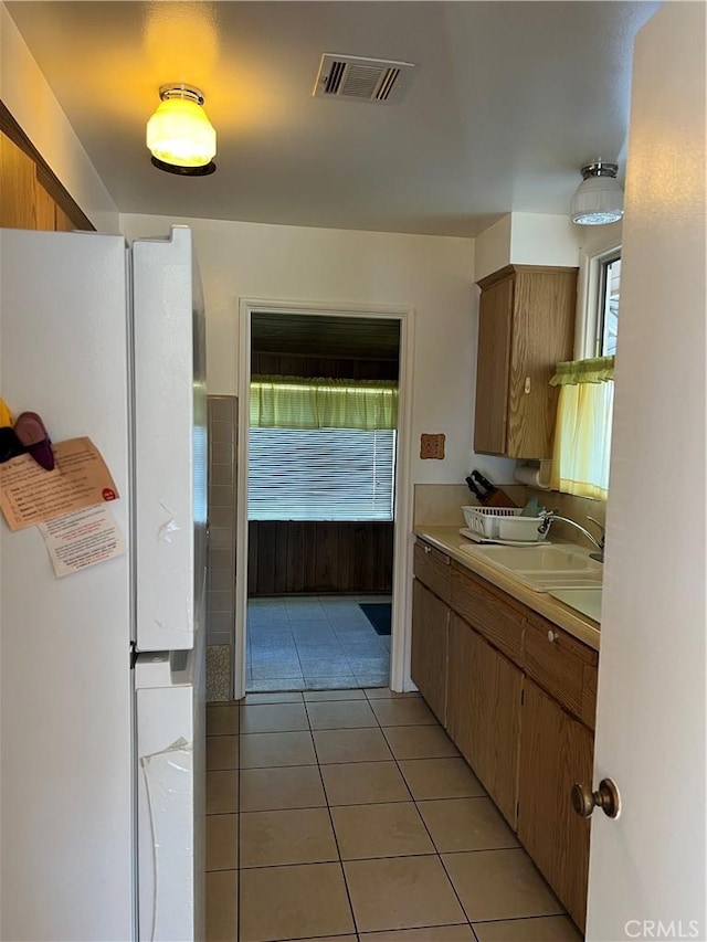 kitchen featuring white refrigerator, plenty of natural light, sink, and light tile patterned floors