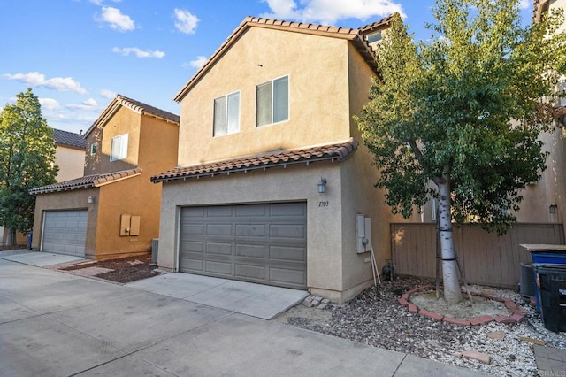 mediterranean / spanish house featuring concrete driveway, an attached garage, a tiled roof, and stucco siding