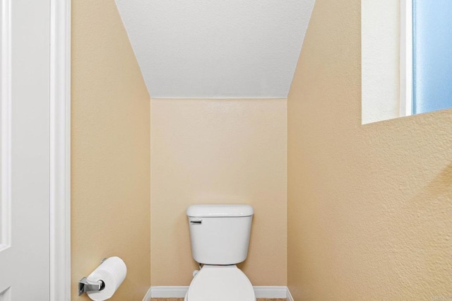 bathroom with toilet, baseboards, and vaulted ceiling