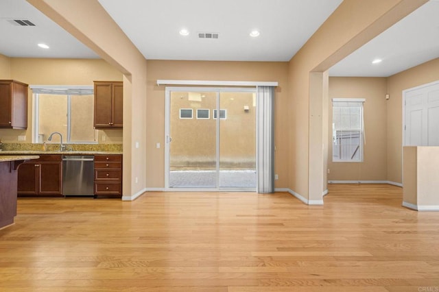 kitchen featuring light stone counters, visible vents, light wood-style flooring, dishwasher, and baseboards