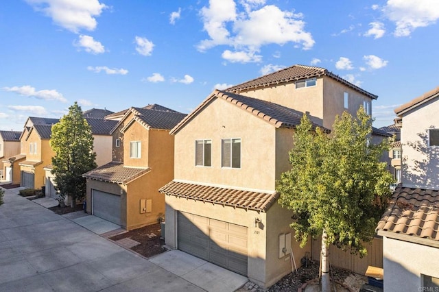 mediterranean / spanish house featuring a garage, a tile roof, driveway, a residential view, and stucco siding