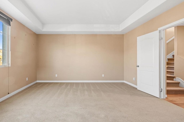 spare room with a raised ceiling, light carpet, plenty of natural light, and stairway