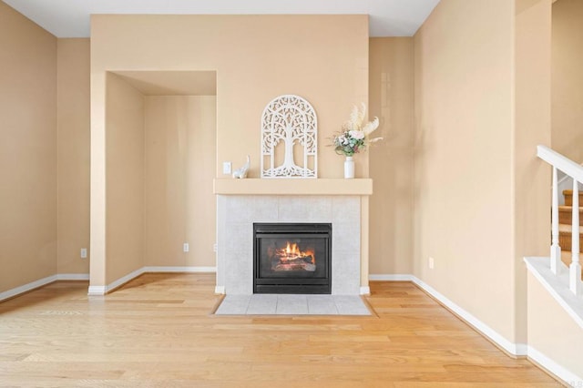 unfurnished living room featuring light wood-type flooring, stairs, baseboards, and a fireplace