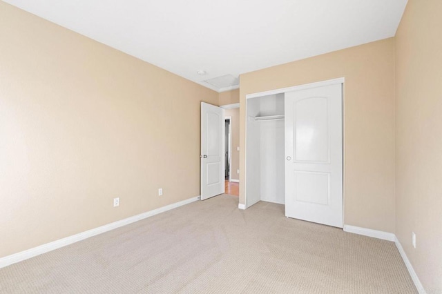 unfurnished bedroom featuring baseboards, a closet, and light colored carpet