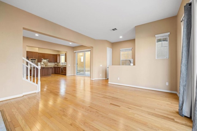 unfurnished living room featuring light wood finished floors, recessed lighting, visible vents, and baseboards