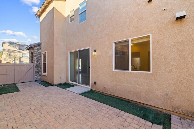 back of property featuring a patio, fence, a gate, and stucco siding