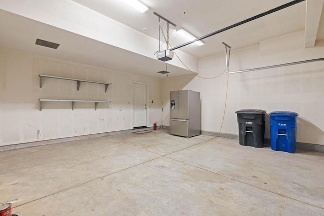 garage featuring a garage door opener and stainless steel fridge