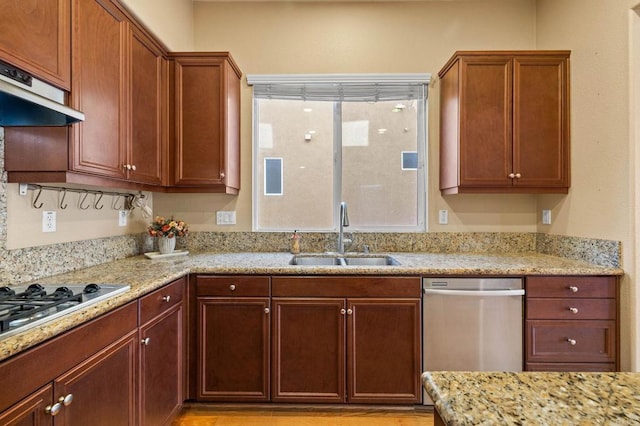 kitchen with under cabinet range hood, light stone counters, and a sink