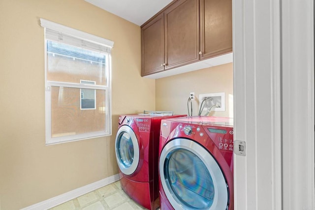 clothes washing area with light floors, baseboards, washer and clothes dryer, and cabinet space