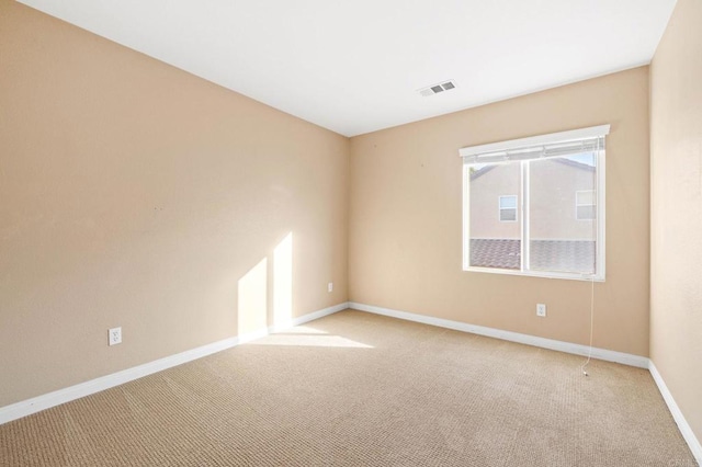 empty room with light colored carpet, visible vents, and baseboards