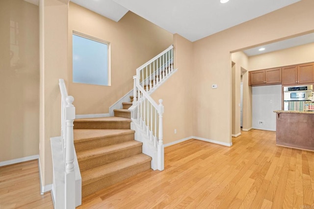 stairs featuring baseboards, wood finished floors, and recessed lighting