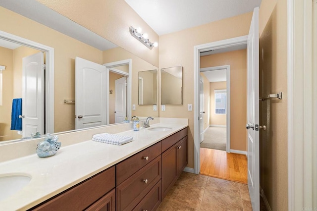 full bath featuring tile patterned floors, a sink, baseboards, and double vanity