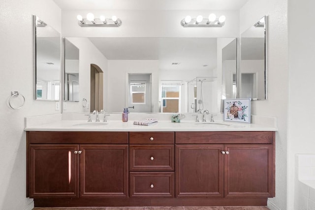 full bathroom featuring a stall shower, a sink, and double vanity