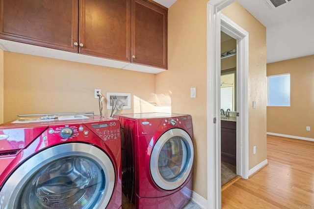 washroom featuring washer and clothes dryer, visible vents, cabinet space, light wood-style floors, and baseboards