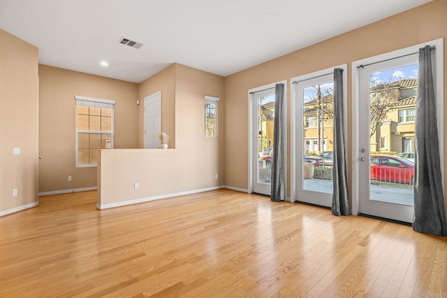 unfurnished room featuring light wood-type flooring, baseboards, and visible vents