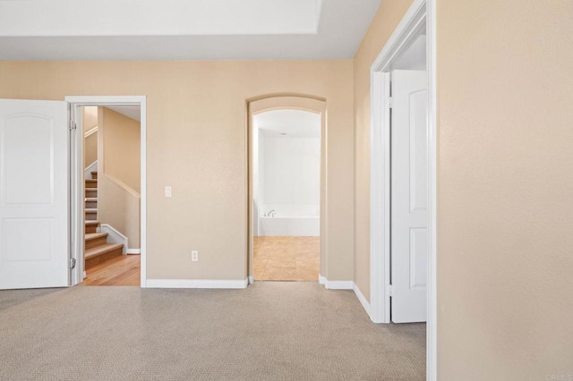 unfurnished bedroom with connected bathroom, light carpet, baseboards, a closet, and a walk in closet