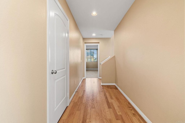 corridor featuring an upstairs landing, light wood-style flooring, baseboards, and recessed lighting