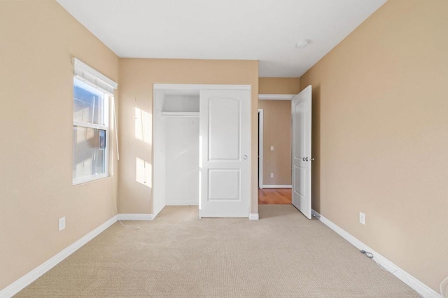 unfurnished bedroom featuring light carpet, a closet, and baseboards