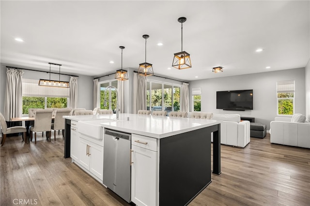 kitchen with stainless steel dishwasher, white cabinets, a kitchen island with sink, and decorative light fixtures