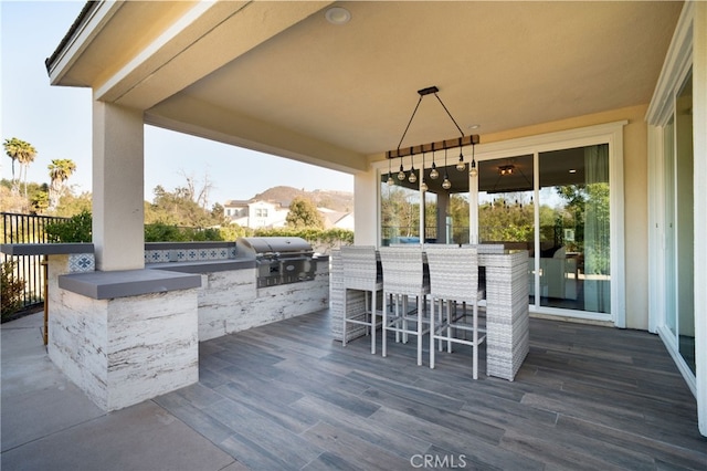 view of patio with a wooden deck, a bar, and area for grilling