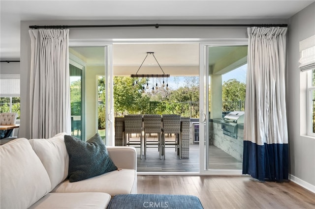 doorway to outside with a wealth of natural light, hardwood / wood-style floors, and a notable chandelier