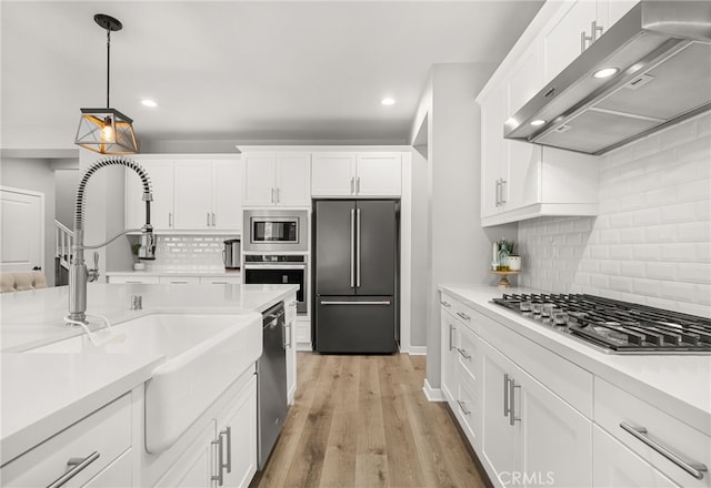 kitchen with range hood, appliances with stainless steel finishes, and white cabinetry