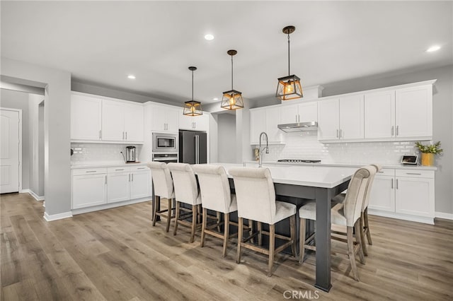 kitchen featuring white cabinets, appliances with stainless steel finishes, and pendant lighting