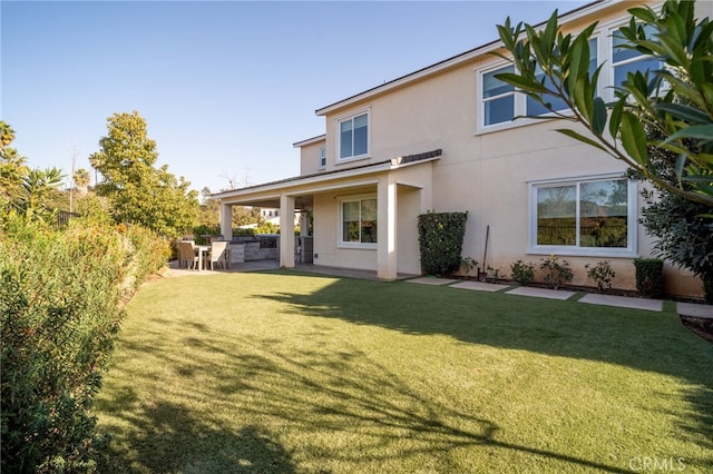 back of house with a lawn and a patio