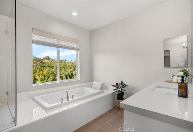 bathroom with tiled tub and vanity