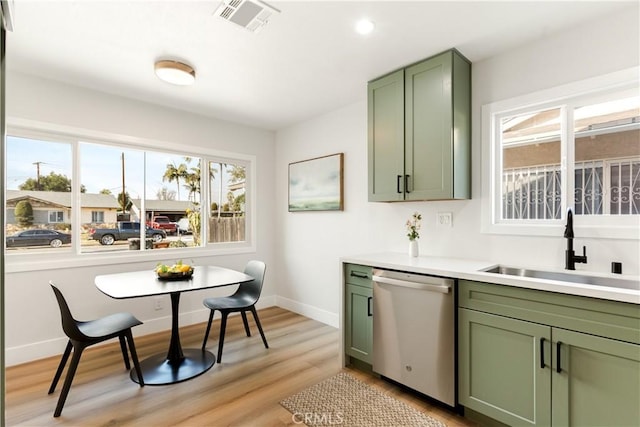 kitchen featuring green cabinetry, dishwasher, light wood-type flooring, and sink