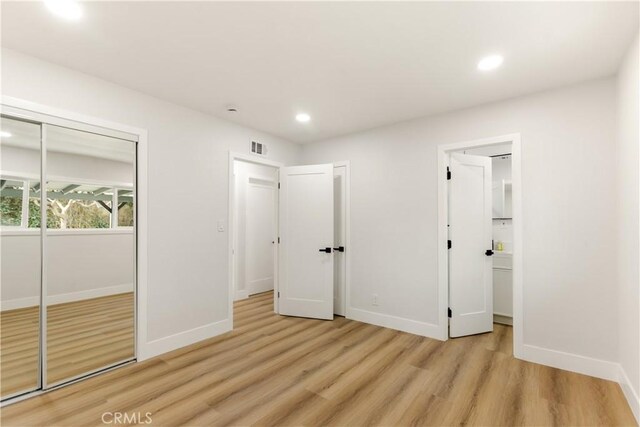 unfurnished bedroom featuring light wood-type flooring and a closet