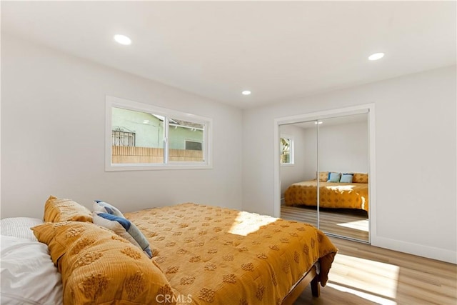 bedroom with hardwood / wood-style flooring, multiple windows, and a closet