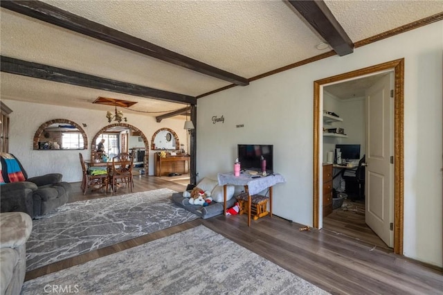 living room featuring wood-type flooring, a textured ceiling, and beamed ceiling