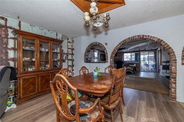 dining area with a chandelier, a textured ceiling, and hardwood / wood-style flooring